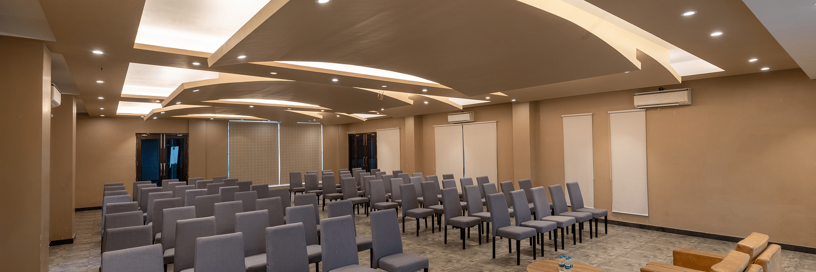 Banquet hall at DLS Forest Vines Resort, with cushioned seating arranged on both sides, a plush sofa, and a table placed in front.